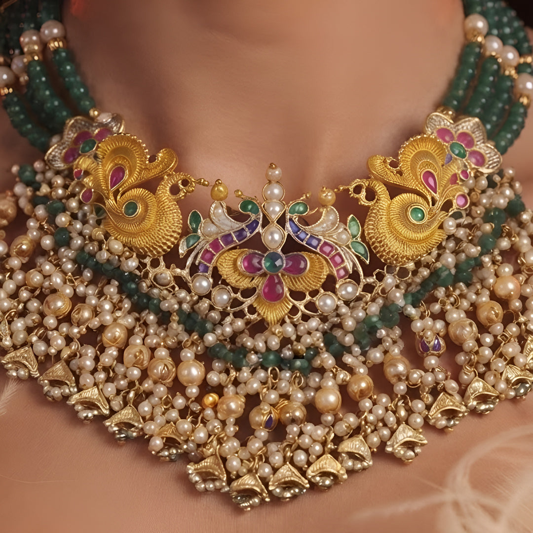 "Antique gold peacock motif necklace and earring set with green beaded strands and pearl drops, traditional temple jewellery on maroon backdrop"