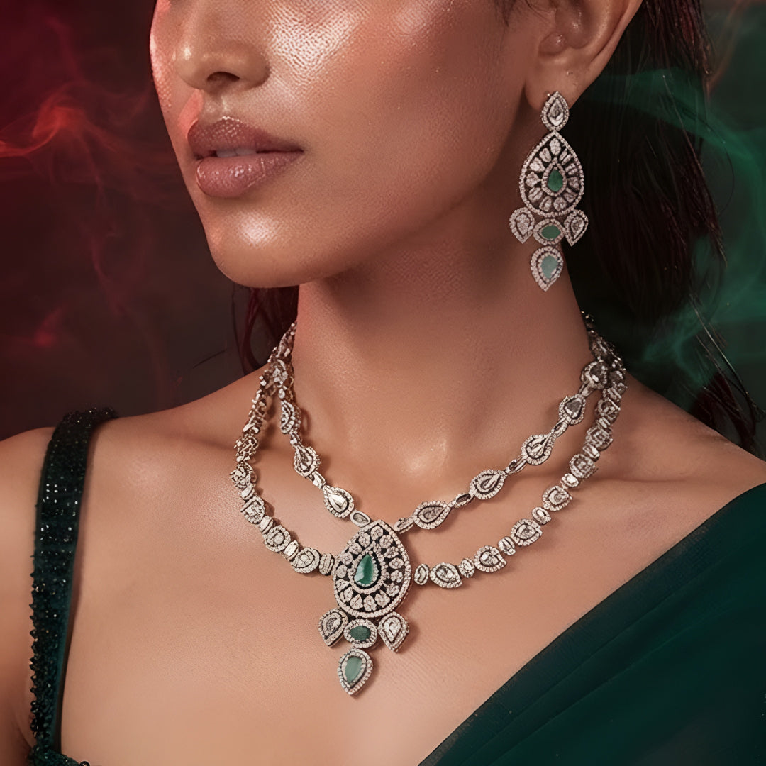 "Antique gold double-strand Kundan necklace with teardrop emerald pendant, matching drop earrings"