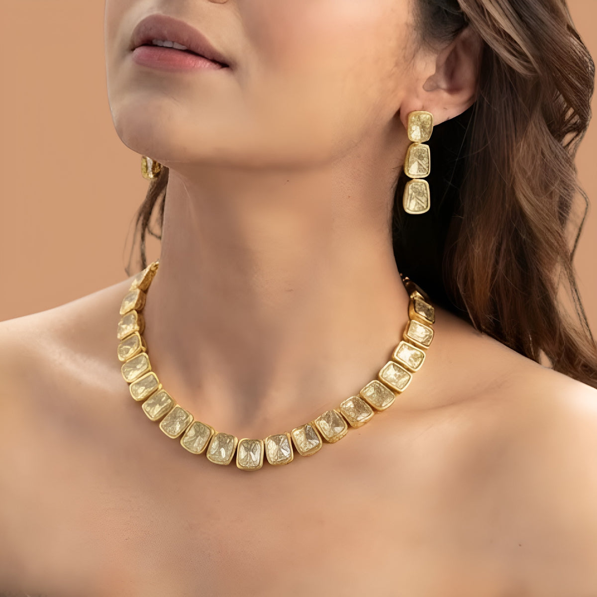 Gold plated polki kundan necklace set with matching drop earrings on red fabric