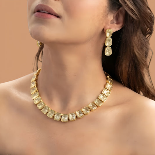 Gold plated polki kundan necklace set with matching drop earrings on red fabric