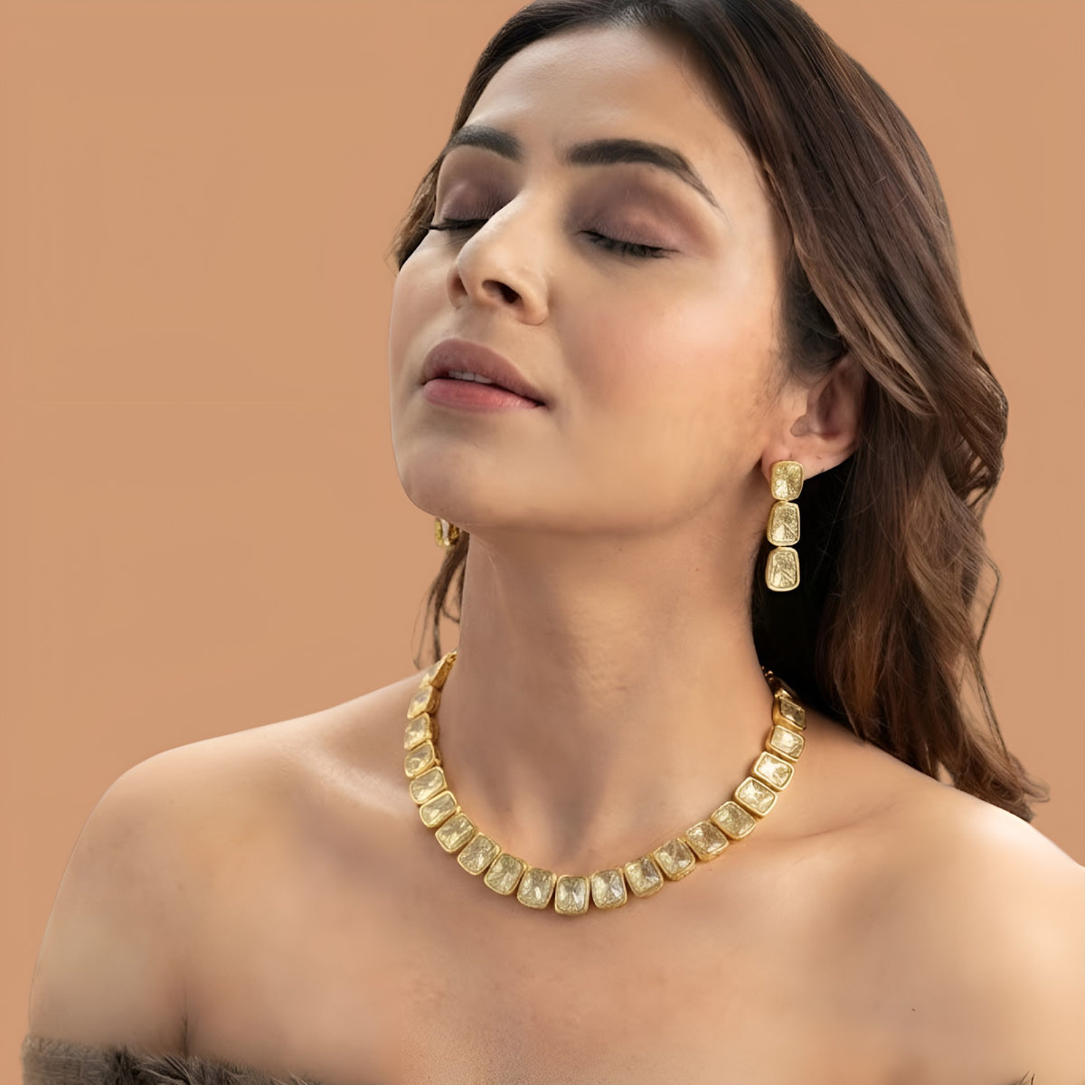 Gold plated polki kundan necklace set with matching drop earrings on red fabric