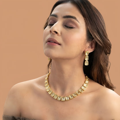 Gold plated polki kundan necklace set with matching drop earrings on red fabric