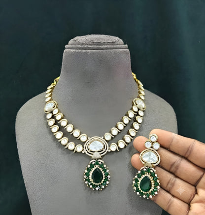 Antique gold two-strand polki kundan necklace with emerald green teardrop pendant on a display bust