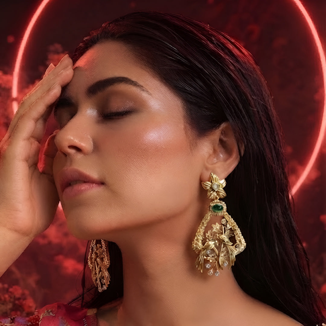 "Antique matte gold bird motif earrings with emerald green stone and CZ accents, floral stud design on dark background"