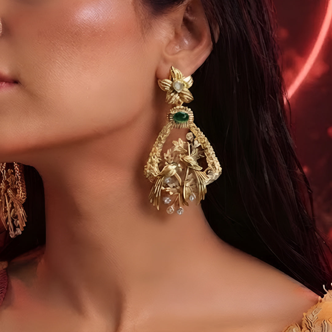 "Antique matte gold bird motif earrings with emerald green stone and CZ accents, floral stud design on dark background"