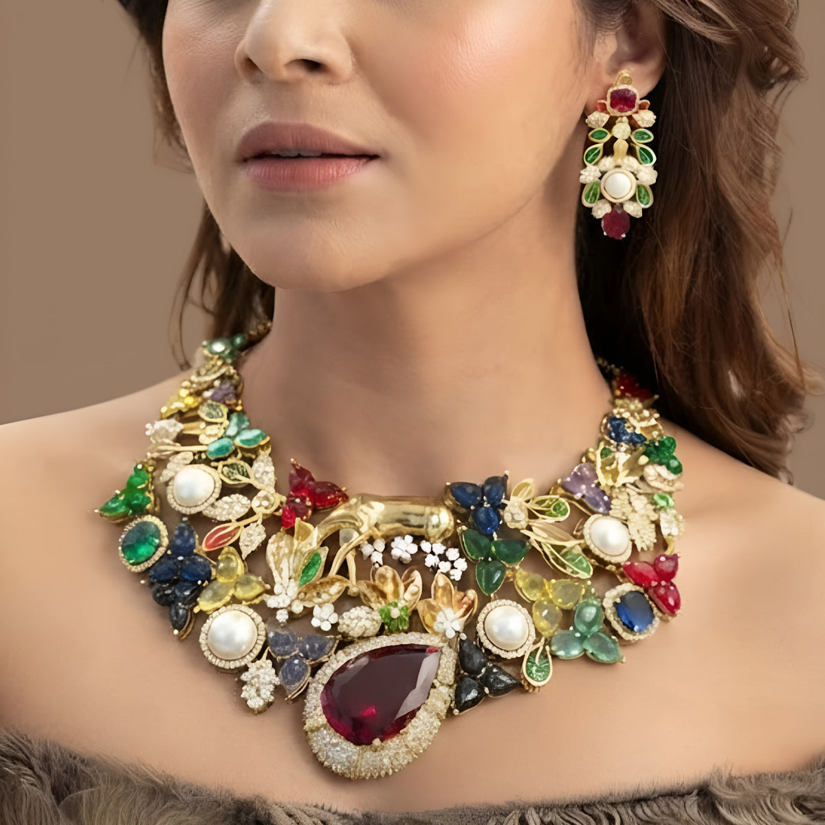 Gold plated multicolour designer necklace with ruby red teardrop centre stone, pearls and deer figure on a display bust