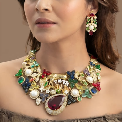 Gold plated multicolour designer necklace with ruby red teardrop centre stone, pearls and deer figure on a display bust