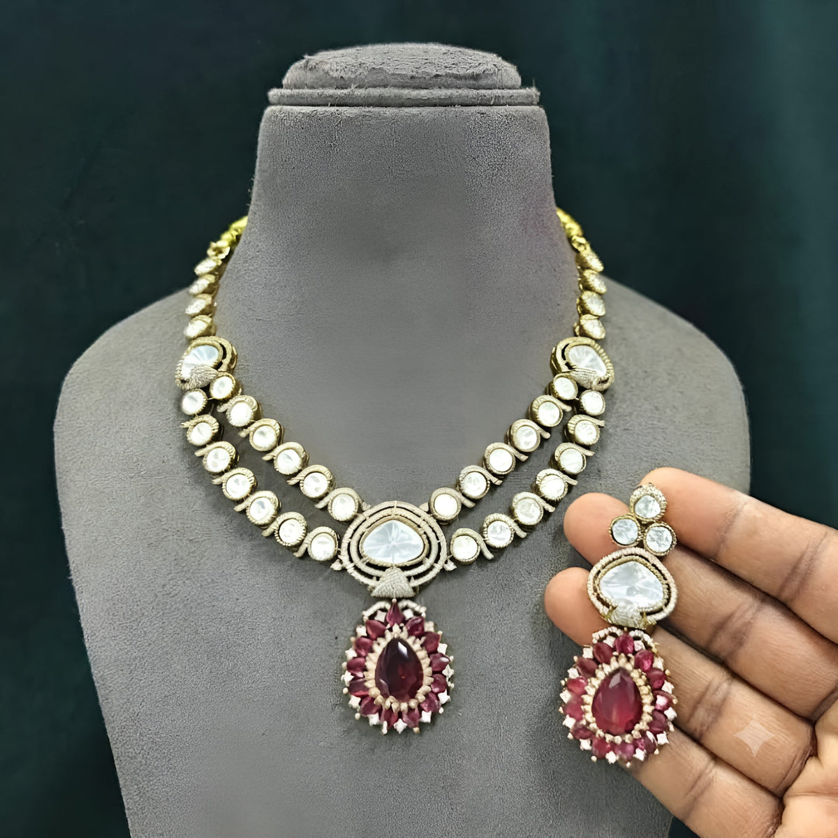 Antique gold two-strand polki kundan necklace with ruby red teardrop pendant on a display bust