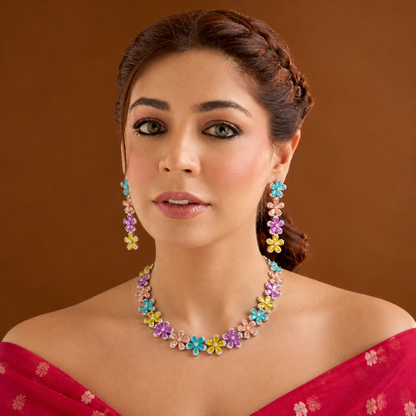 Silver plated multicolour flower American diamond necklace set with aqua, peach, pink and yellow stones and matching drop earrings on a marble slab