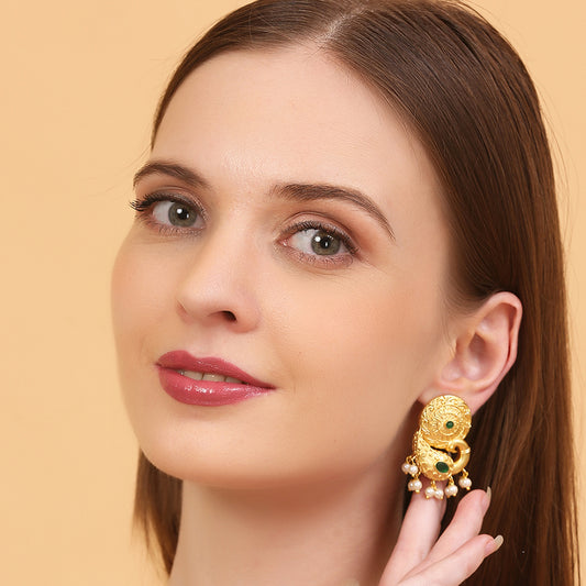 Gold peacock temple earrings with green stone accents and pearl drop detailing on neutral background