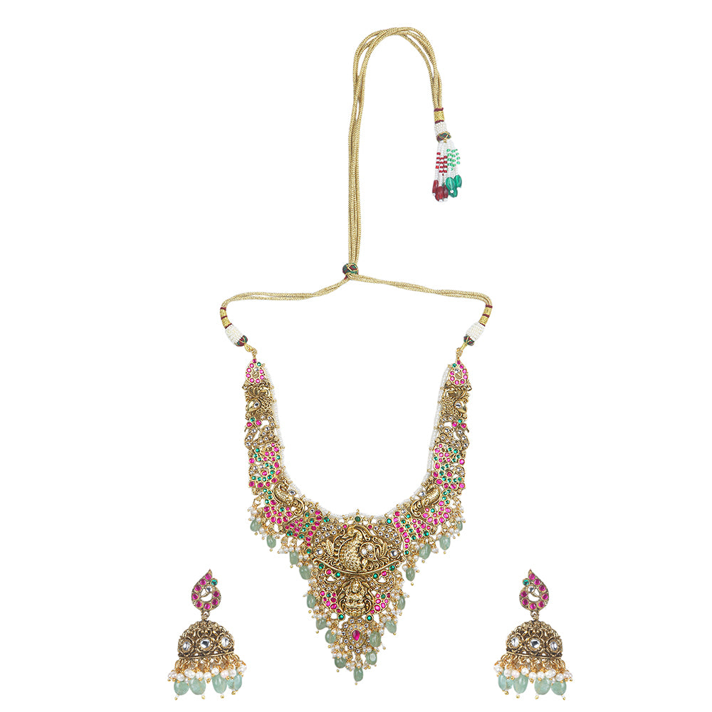 Gold plated temple Lakshmi bridal necklace set with pink green stones and jhumka earrings with pearl and bead drops on white background