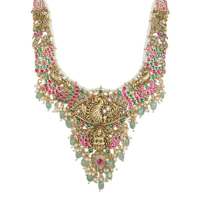 Gold plated temple Lakshmi bridal necklace set with pink green stones and jhumka earrings with pearl and bead drops on white background