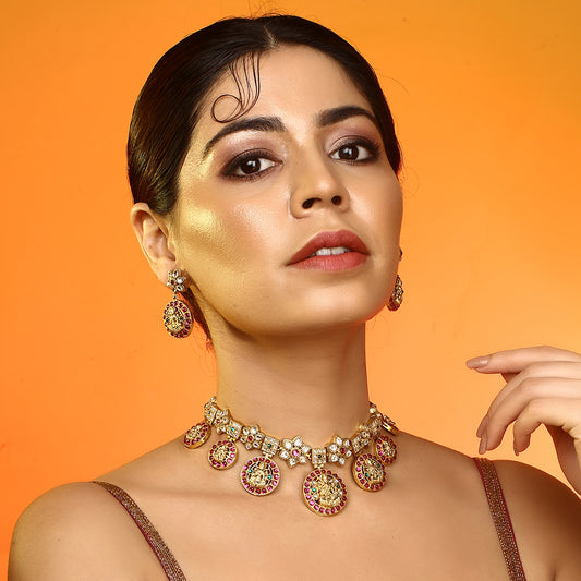 Gold plated Lakshmi coin necklace set with pink stones and matching earrings on white background