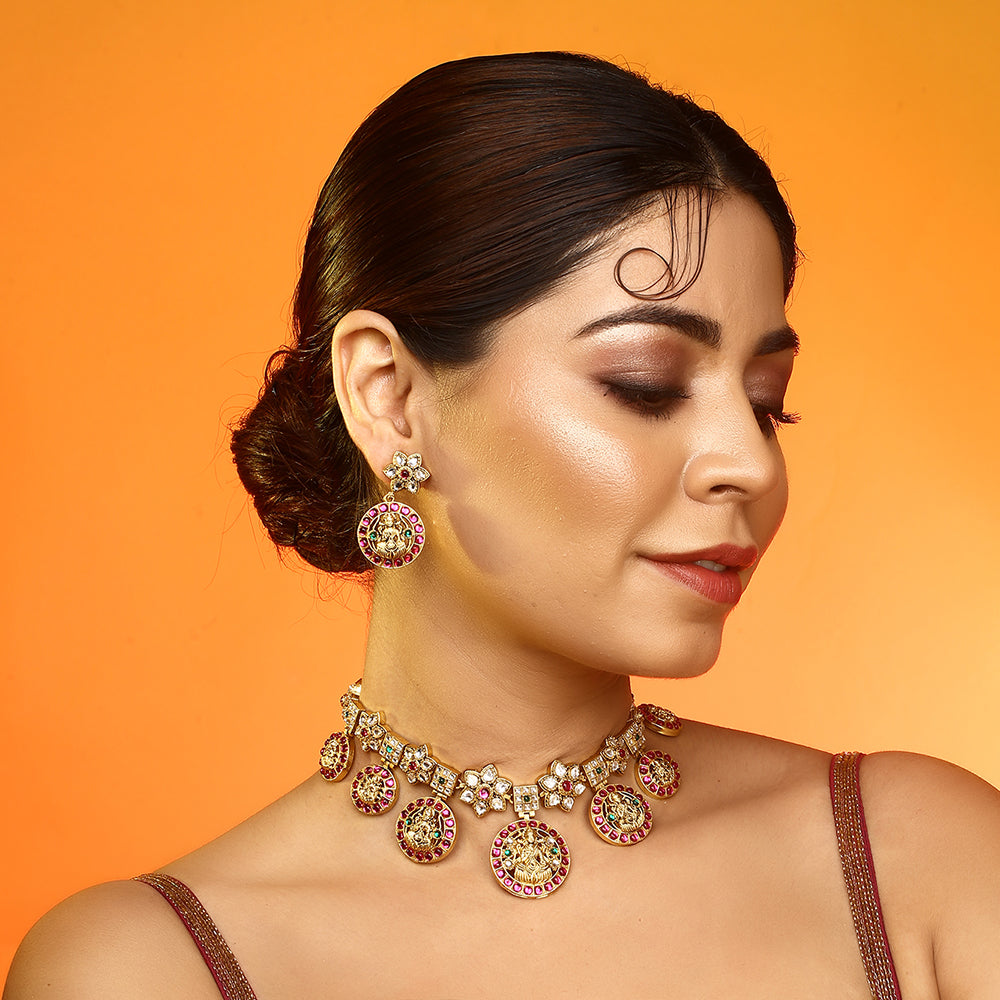 Gold plated Lakshmi coin necklace set with pink stones and matching earrings on white background