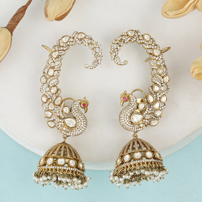 Gold plated peacock design jhumka earrings with American diamonds and pearl drops on white background