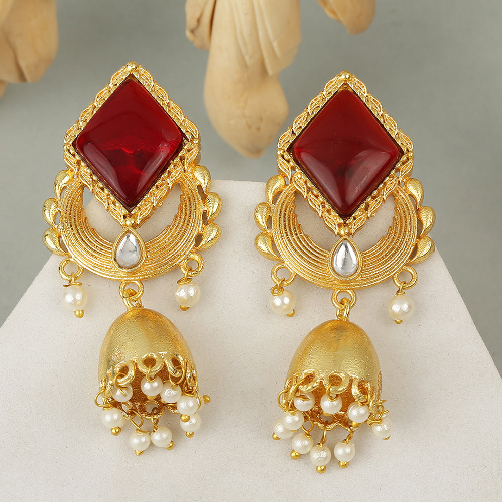 Gold jhumka earrings with red gemstone top, circular design, and pearl drop danglers on neutral background