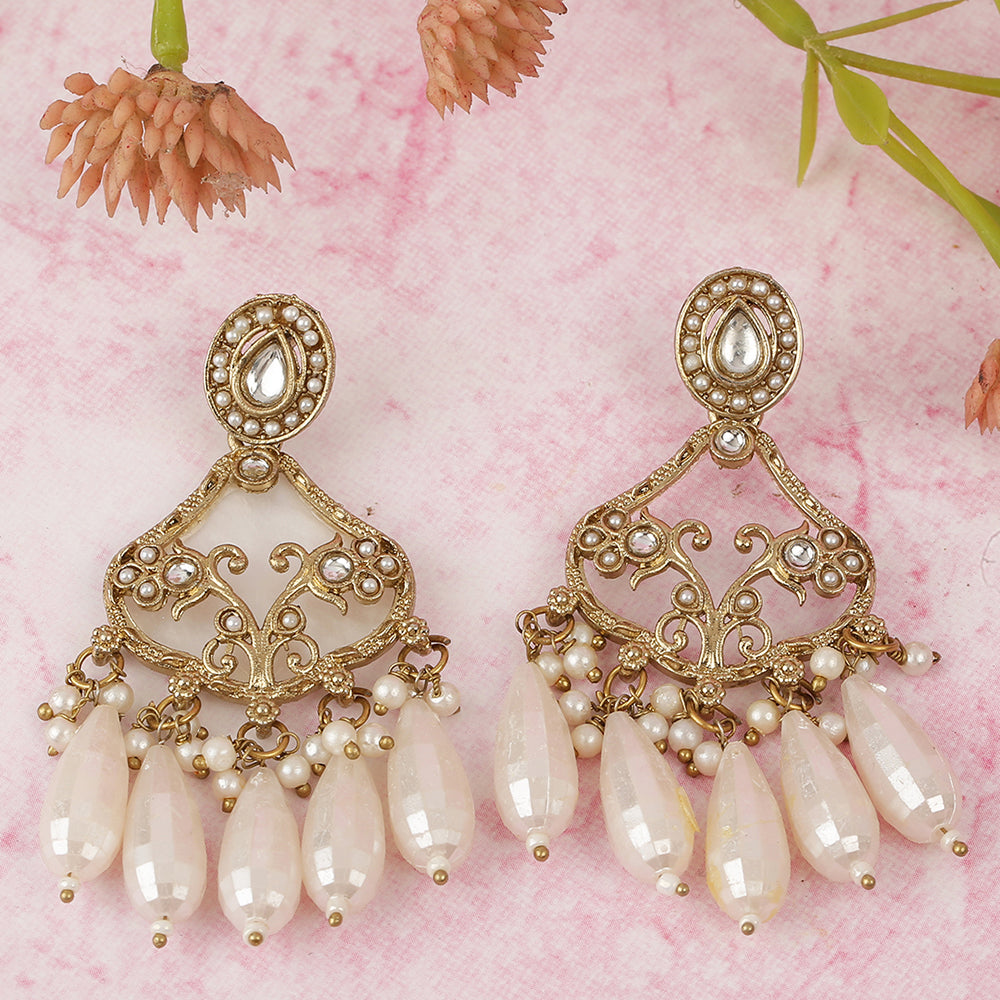 Gold chandelier earrings with kundan stone top and pearl drop danglers on pink background