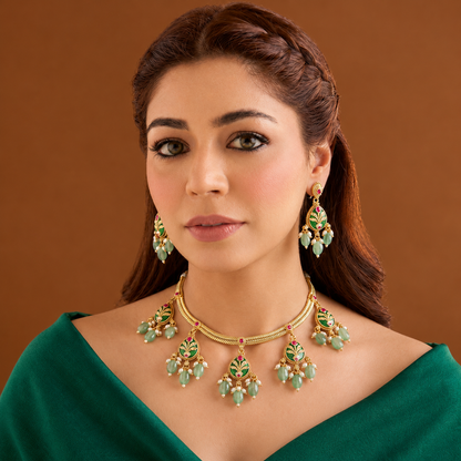 Antique gold plated necklace set with dark green pear medallions, pink stones, mint green bead and pearl drops and matching earrings on a blue bust