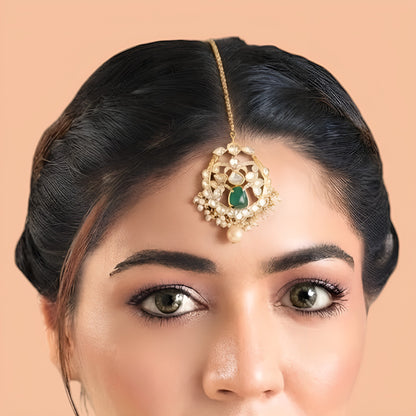 Gold-plated kundan polki style maang tikka with emerald green centre stone, clear floral medallion, pearl fringe, pearl drop and box chain with hook