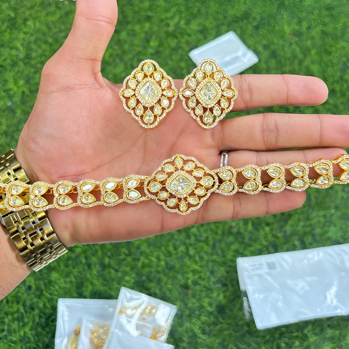 Gold plated polki kundan choker necklace set with matching diamond-shaped stud earrings held in hand