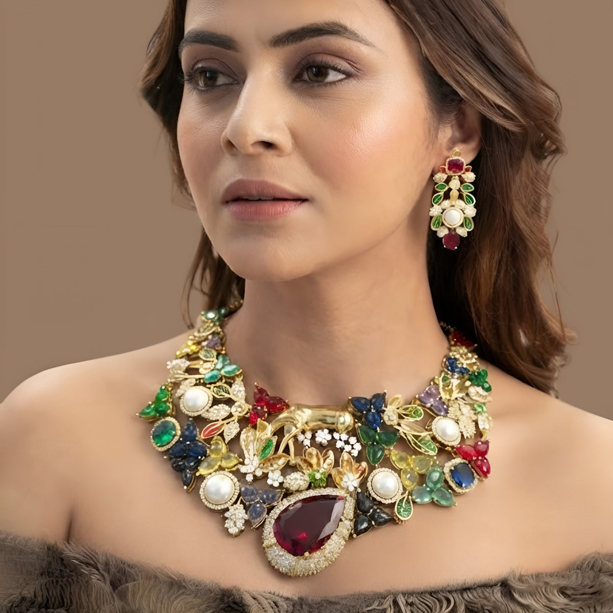 Gold plated multicolour designer necklace with ruby red teardrop centre stone, pearls and deer figure on a display bust