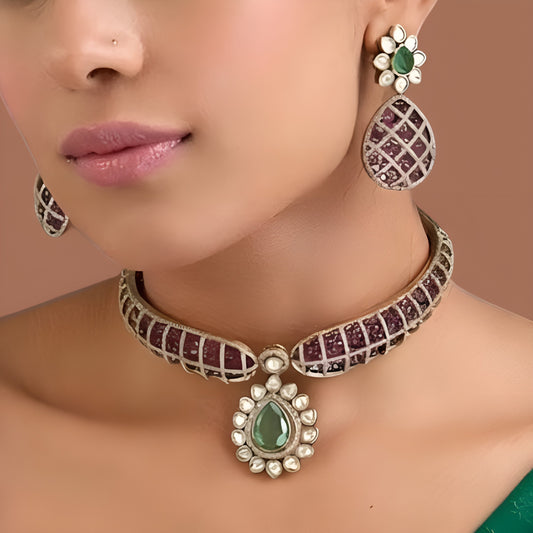 Gold-tone designer necklace set with ruby-pink and green teardrop stones, white stone detailing, and matching drop earrings.