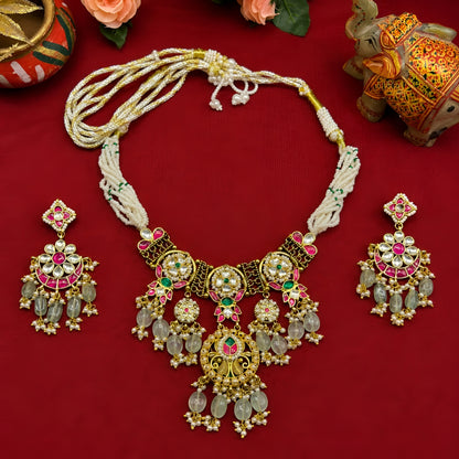 "Antique gold Kundan necklace and earring set with multi-strand pearl beading, ruby-green stone work, peacock detail and green bead drops, traditional jewellery on maroon backdrop"