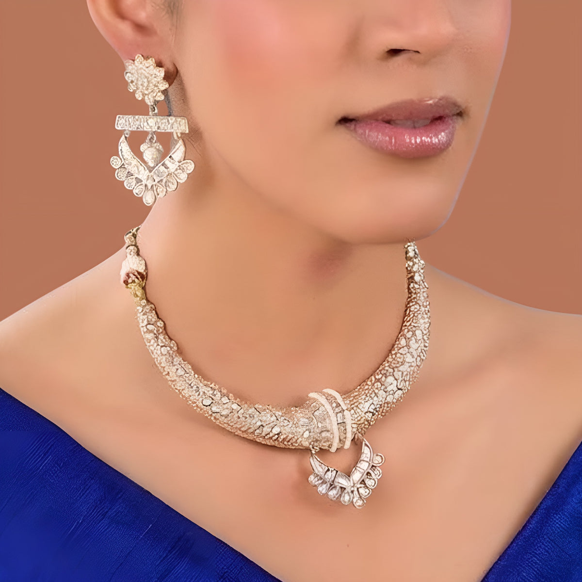 Gold-tone American Diamond designer necklace with textured stone detailing, statement pendant, and matching drop earrings styled on a model.