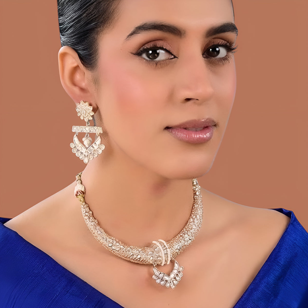 Gold-tone American Diamond designer necklace with textured stone detailing, statement pendant, and matching drop earrings styled on a model.