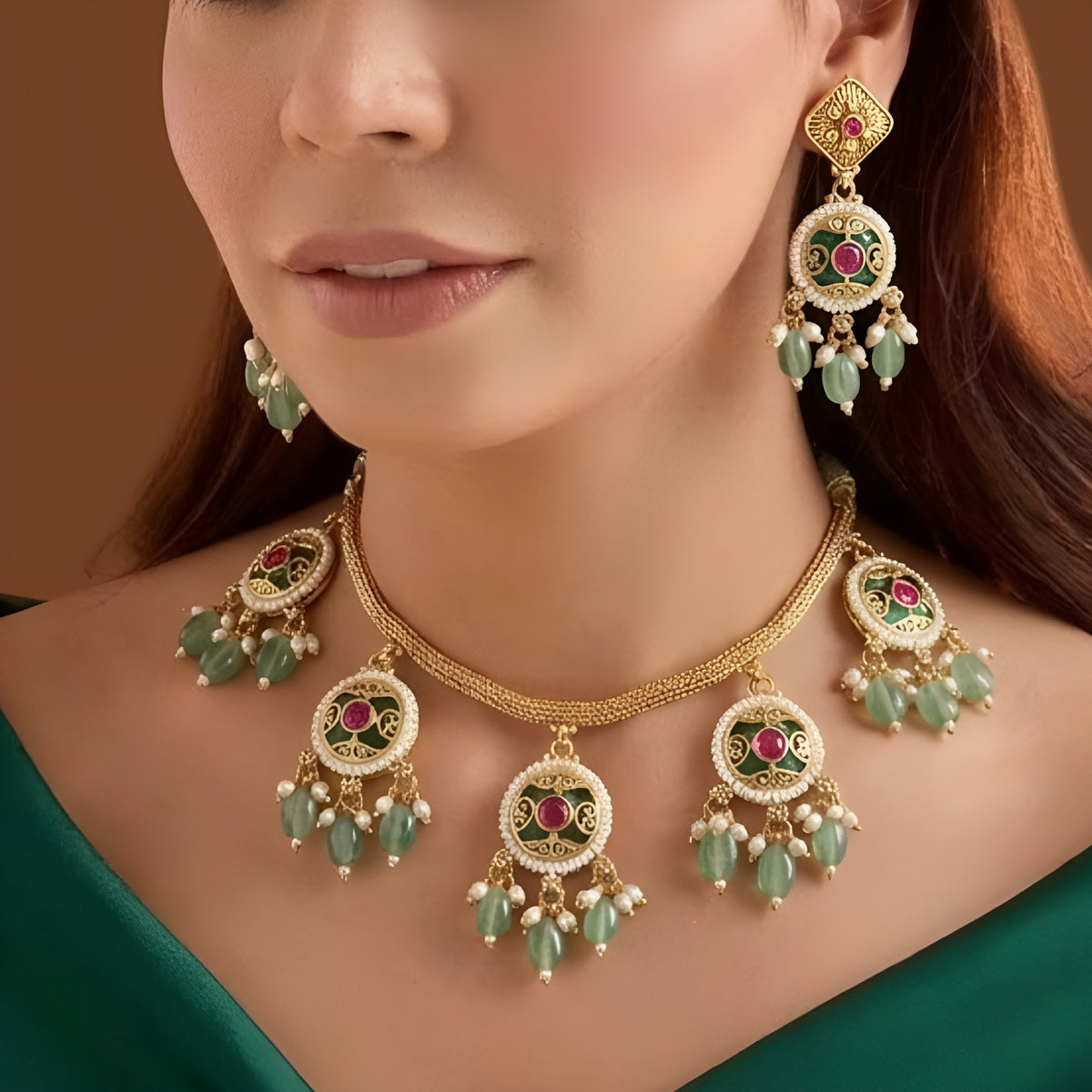 Antique gold plated necklace set with round ruby pink medallions, pastel green bead and pearl drops and matching earrings on a blue bust