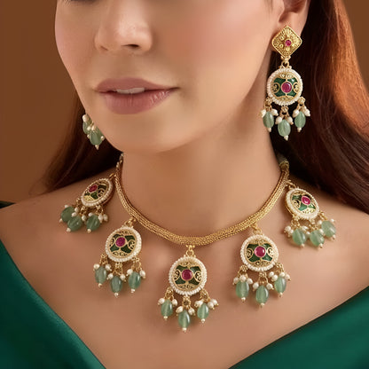 Antique gold plated necklace set with round ruby pink medallions, pastel green bead and pearl drops and matching earrings on a blue bust