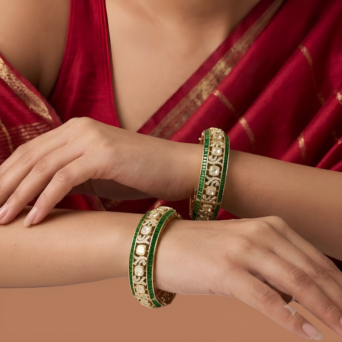 Pair of gold-finish openable kada bangles with emerald-green baguette stones, polki-style clear cushion-cut stones, and Victorian-style American diamond scrollwork