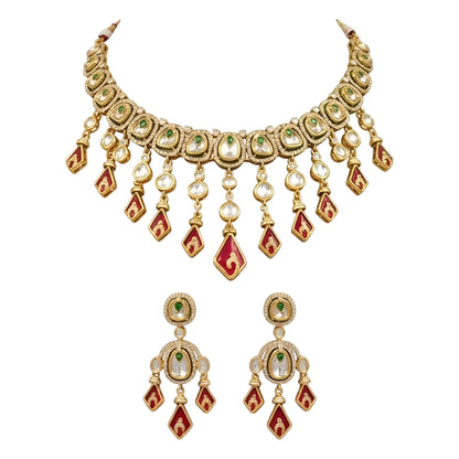 Gold-tone kundan necklace set with red kite-shaped drops, green accent stones and matching chandelier earrings on a grey display bust