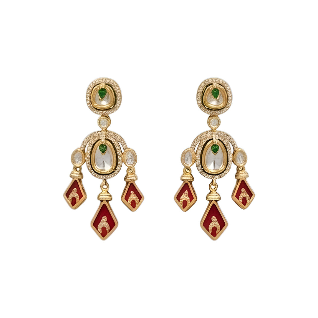 Gold-tone kundan necklace set with red kite-shaped drops, green accent stones and matching chandelier earrings on a grey display bust