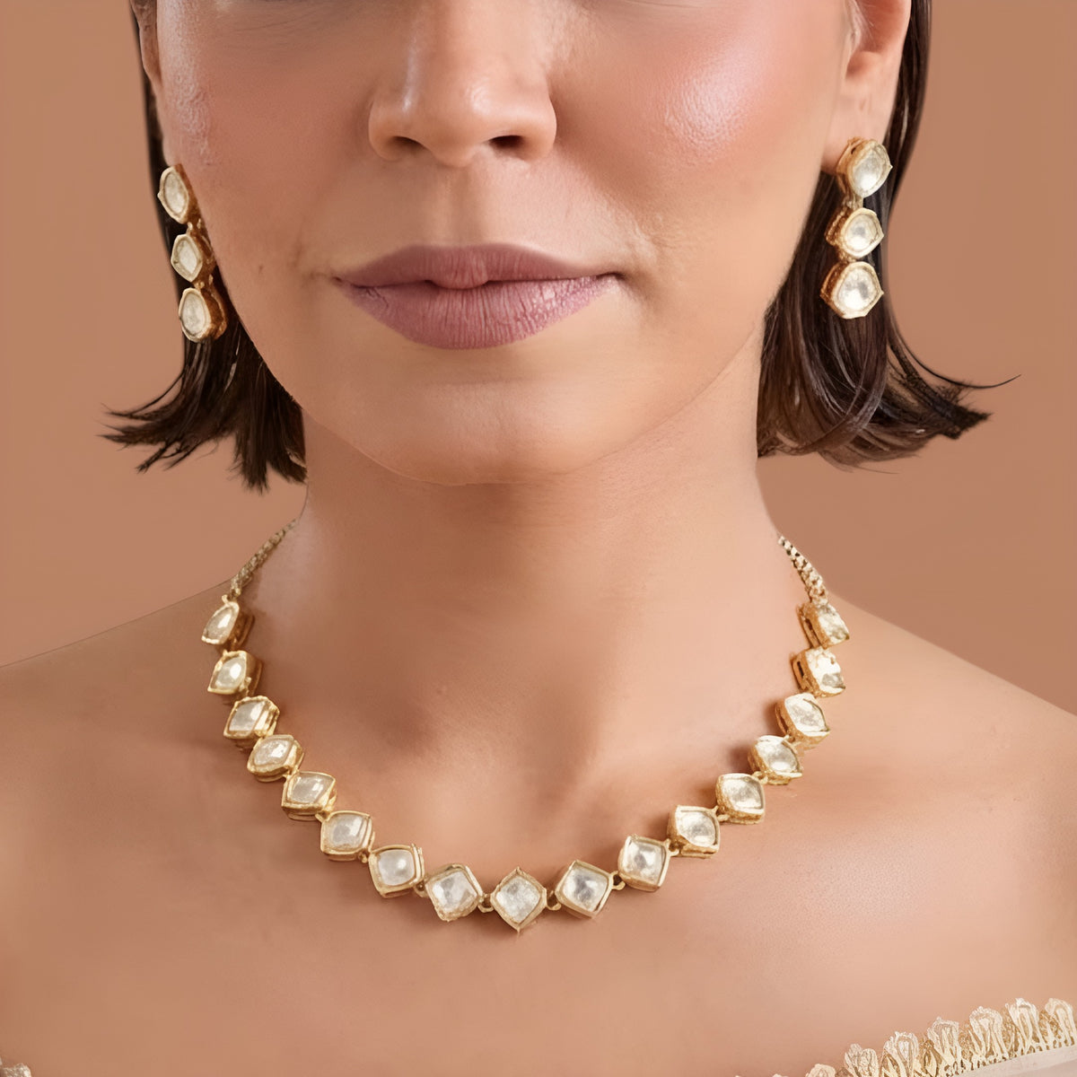 Gold plated hexagon zircon necklace set with matching drop earrings on a cream background