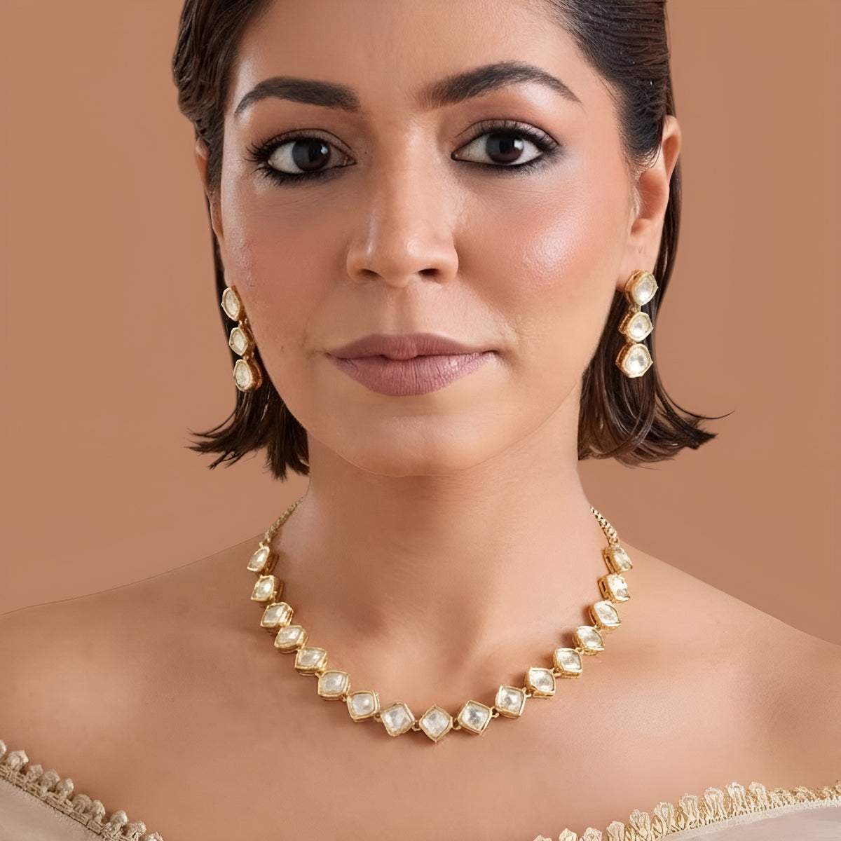 Gold plated hexagon zircon necklace set with matching drop earrings on a cream background
