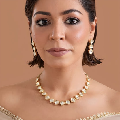 Gold plated hexagon zircon necklace set with matching drop earrings on a cream background