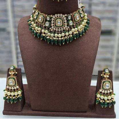 Gold kundan choker necklace set with green meenakari motifs, pearl and green bead drops and matching chandelier earrings on brown bust