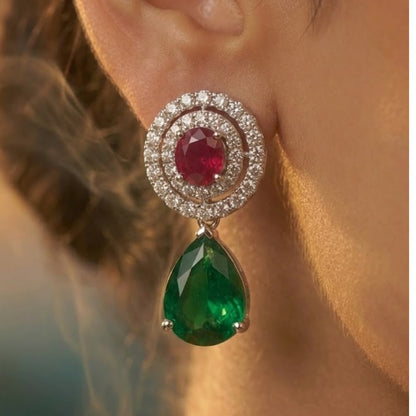 Luxury emerald green and ruby stone diamond-finish necklace set with matching earrings on white background.