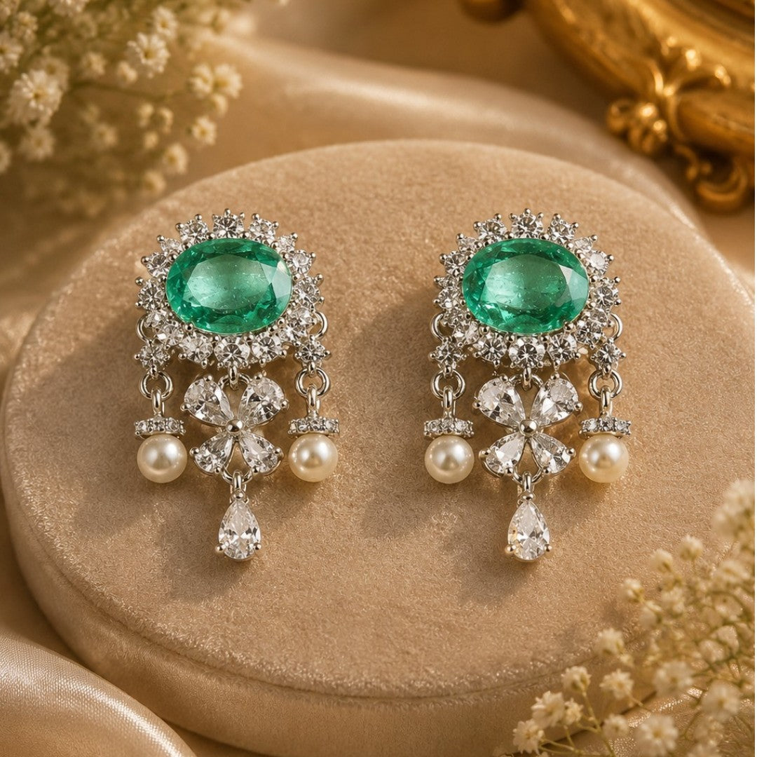 "Silver rhodium-plated drop earrings with oval emerald stone, diamond halo, clover-shaped white stones and pearl bead accents"