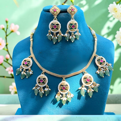 Antique gold plated choker necklace set with ruby pink medallions, mint green bead and pearl drops and matching earrings on a blue bust