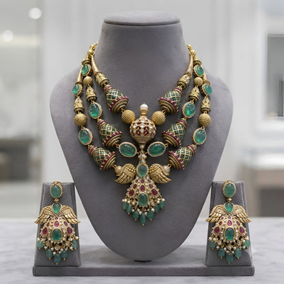 "Antique gold plated kundan polki bridal necklace set with emerald and ruby stones, peacock wing pendant design, and matching jhumka earrings"
