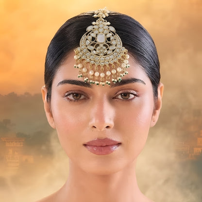 Gold kundan maang tikka with pearl and green bead tassels, traditional Indian bridal hair jewelry on white background