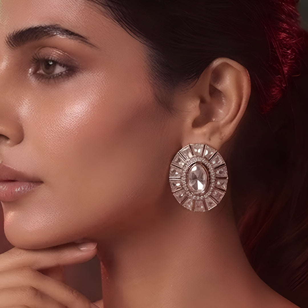 Pair of rose gold-plated oval stud earrings with white stone sunburst halo design on white