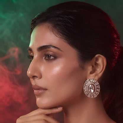 Pair of rose gold-plated oval stud earrings with white stone sunburst halo design on white