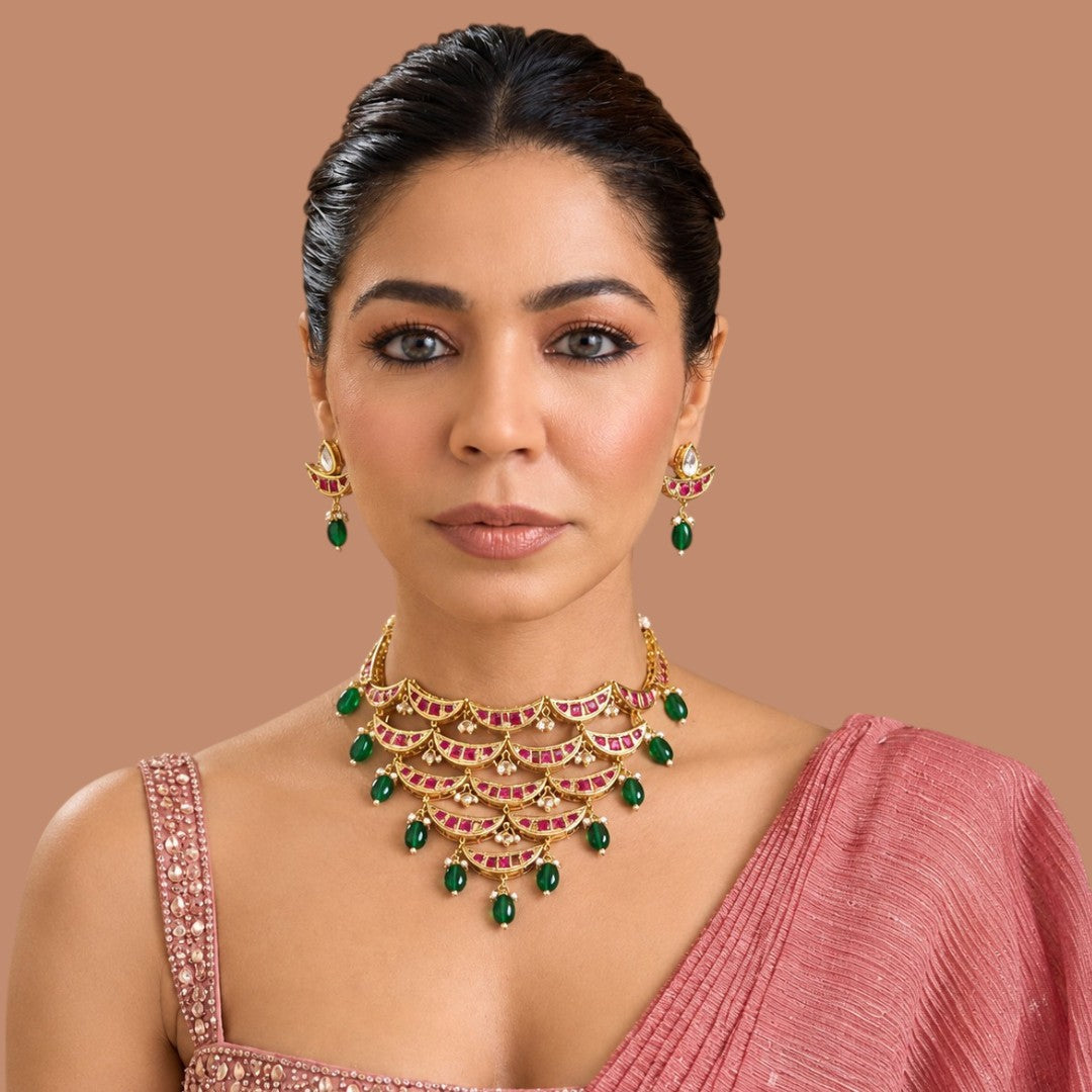 Gold-finish kundan crescent-tier necklace set with ruby-pink stones, green bead and pearl hangings and matching pear-top earrings