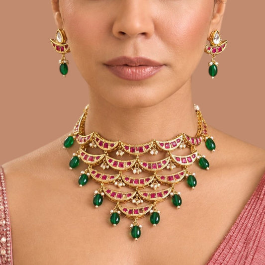 Gold-finish kundan crescent-tier necklace set with ruby-pink stones, green bead and pearl hangings and matching pear-top earrings
