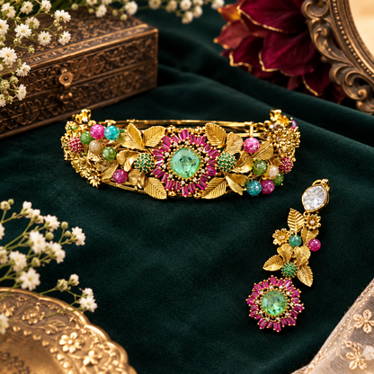 Antique gold rigid choker with leaf and flower design, ruby-pink baguette flower, mint-green centre stone and multicolour beads with matching drop earring on a grey display bust