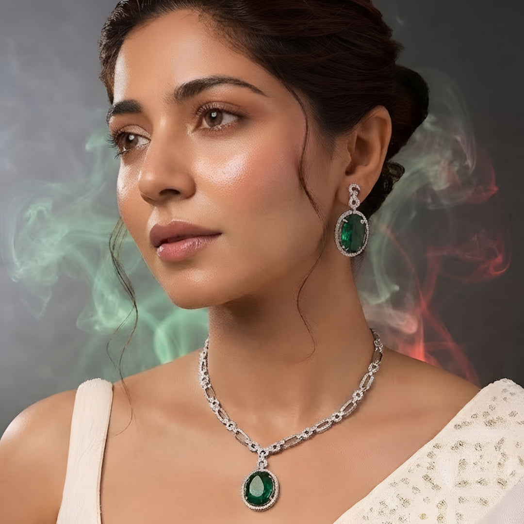 Silver plated American Diamond necklace set with emerald green oval pendant and matching drop earrings on white background
