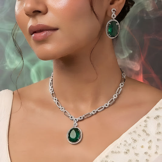 Silver plated American Diamond necklace set with emerald green oval pendant and matching drop earrings on white background